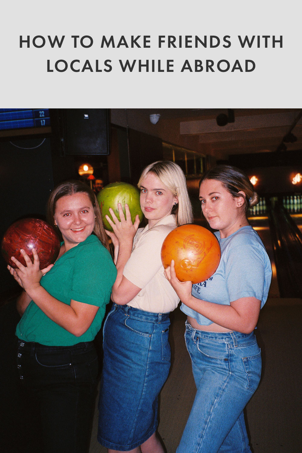 Three friends smiling and holding bowling balls