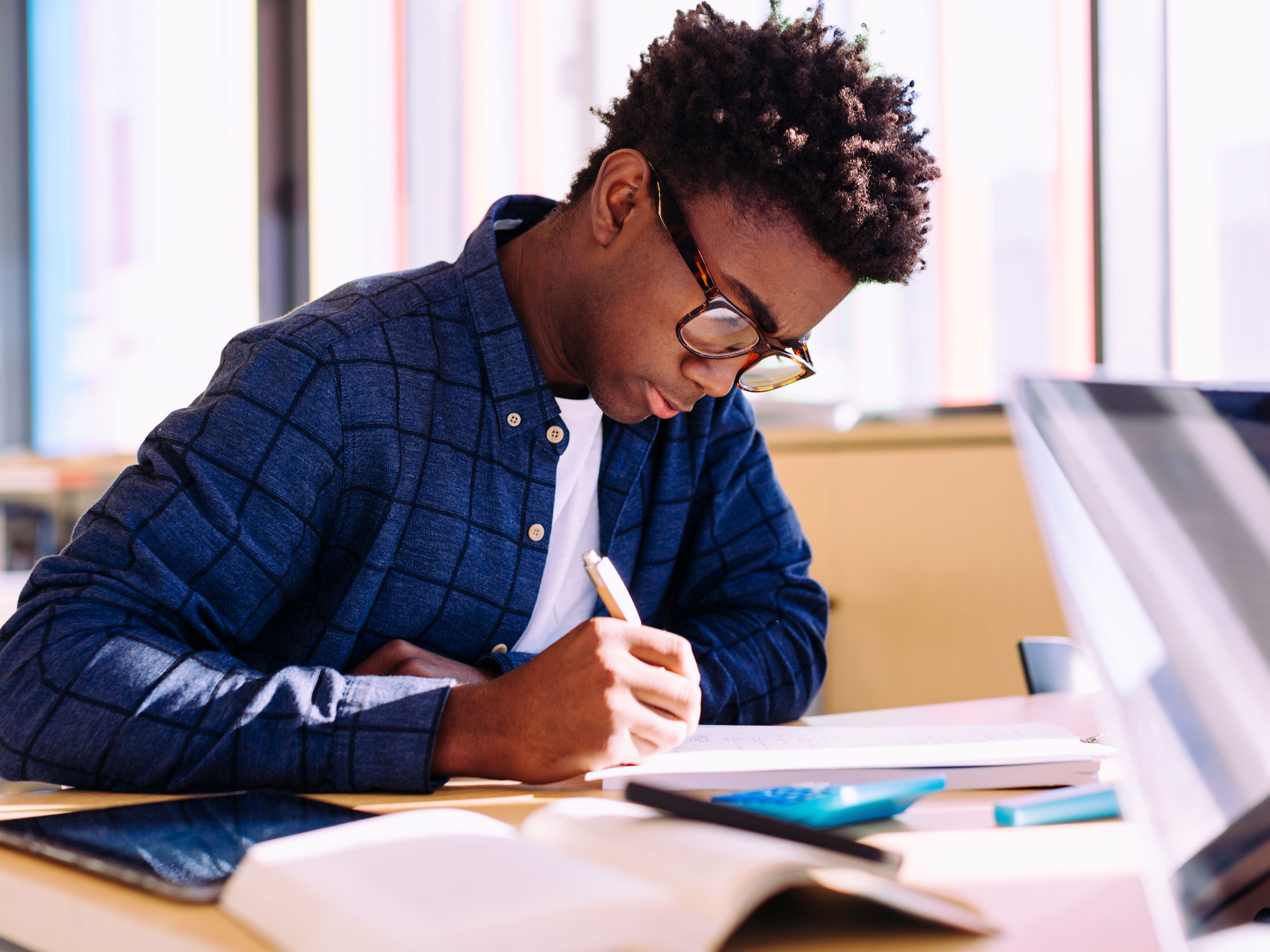 Student writing at a desk