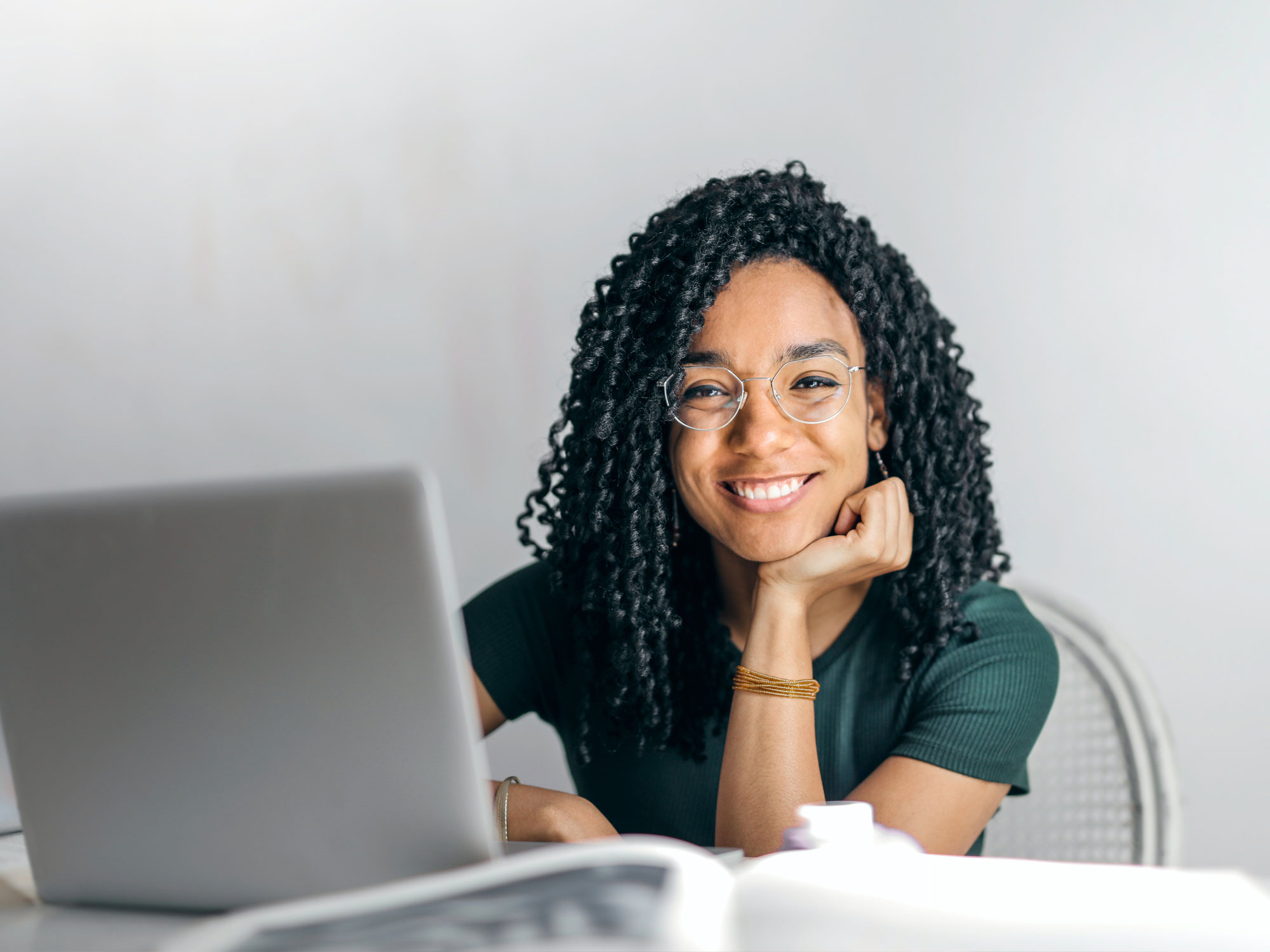 Student sitting at a desk smiling near a computer