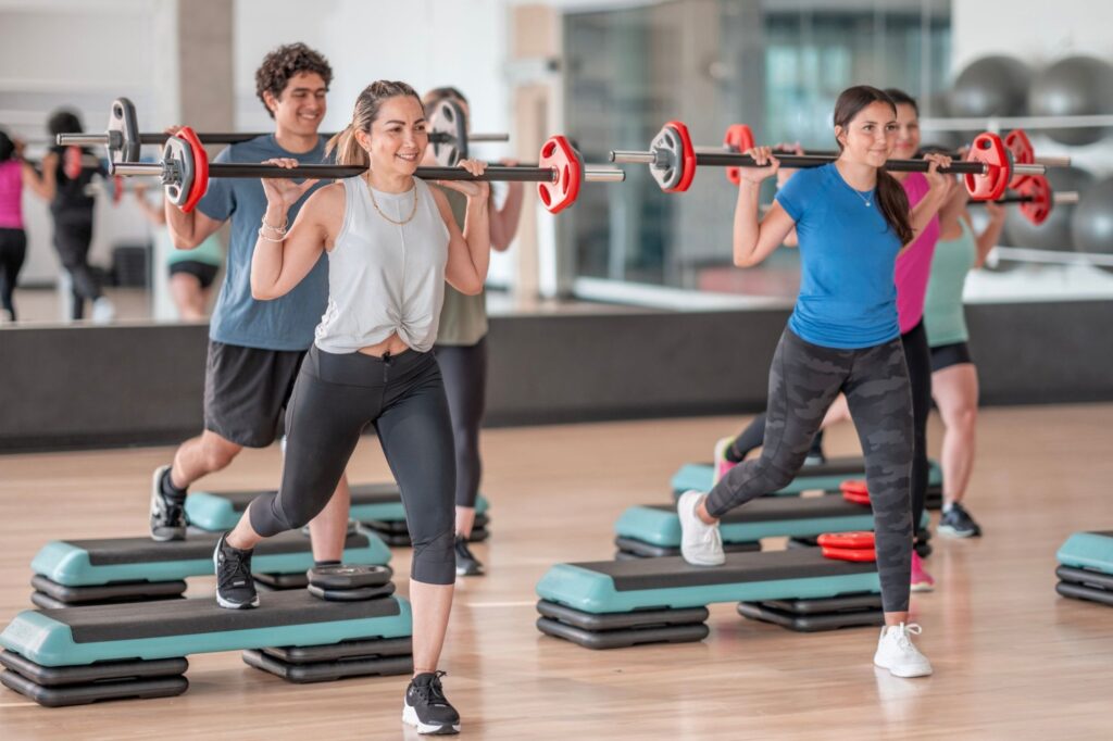 Students working out with steps and barbells indoors