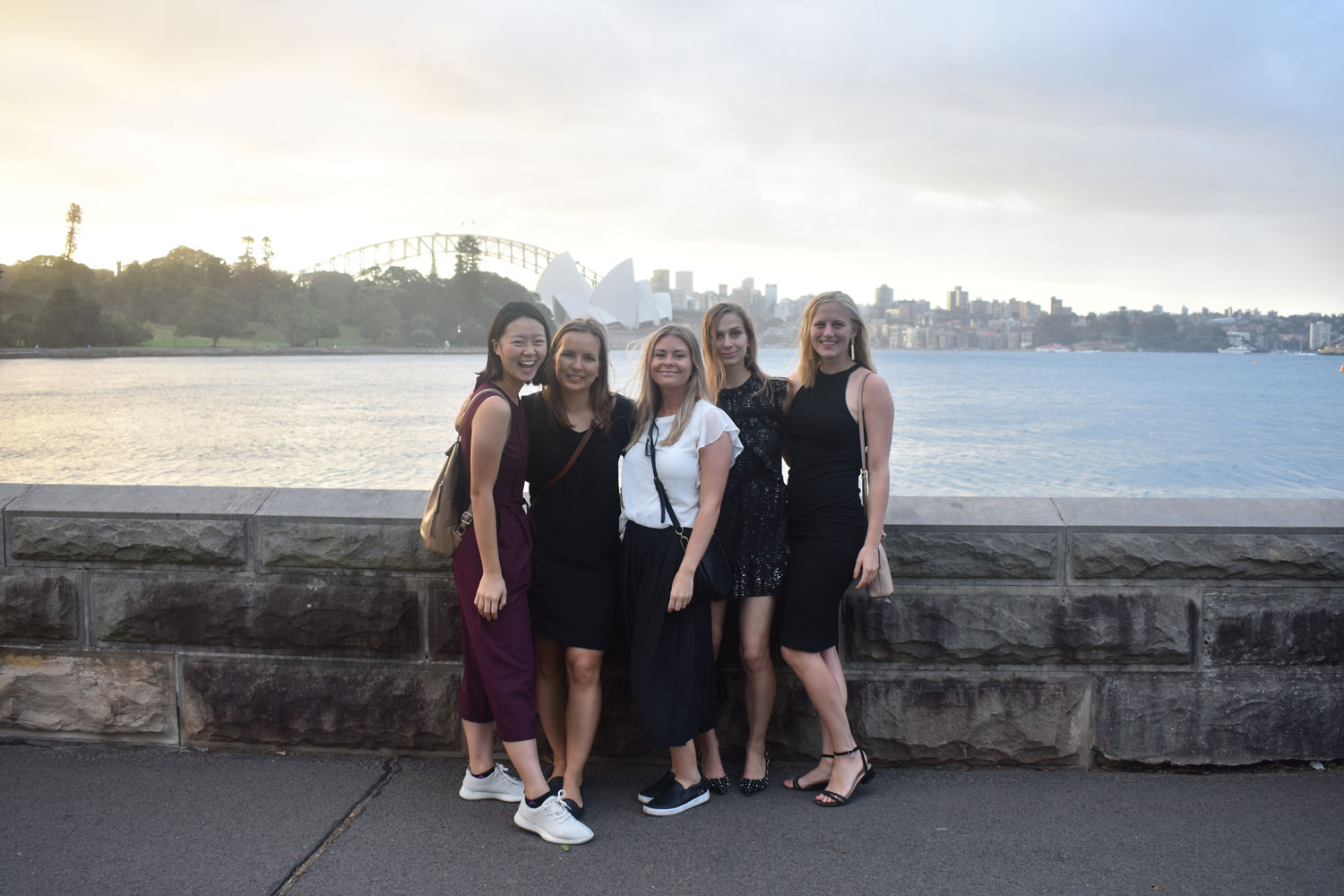 Waresa smiling with a group of gals, standing in front of a beautiful ocean scene