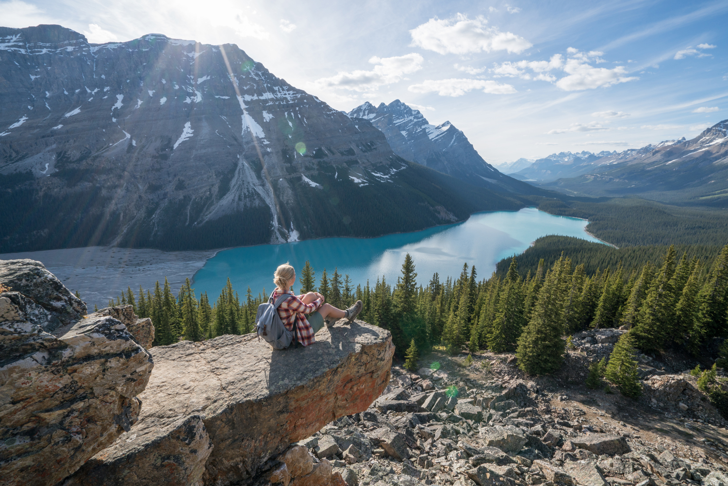 Hiking girl reaching mountain top and sits to look at view