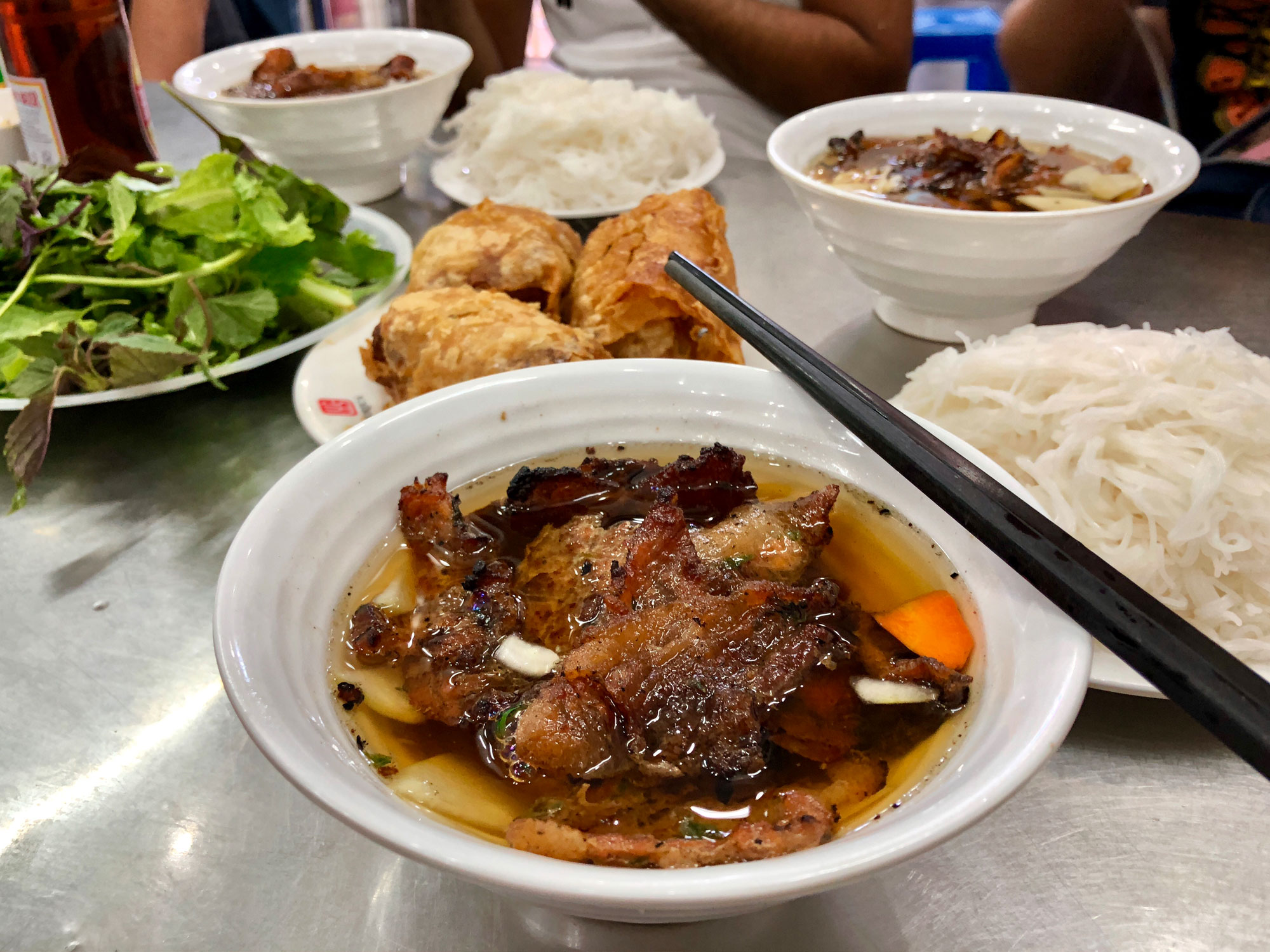 Bun Cha in a bowl with other foods in the backgorund.