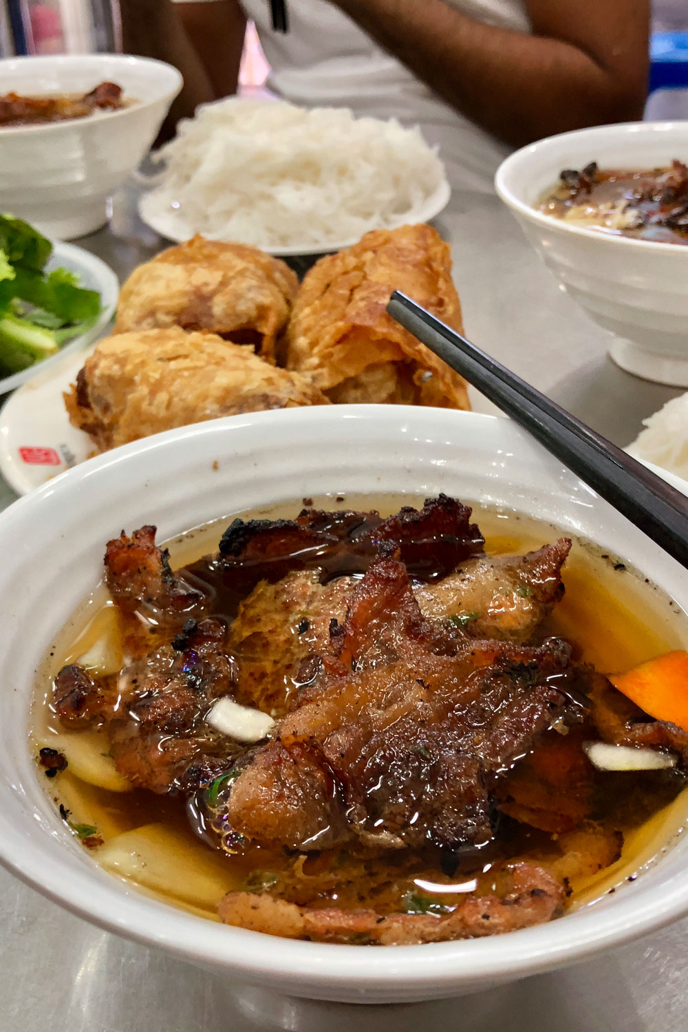 Bun Cha in a bowl with other foods in the backgorund.
