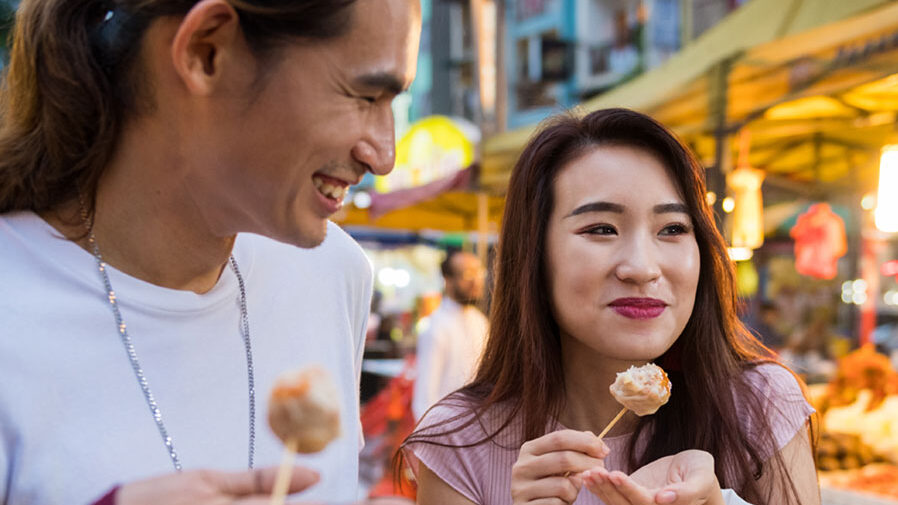 Two friends eating street food in Asia.