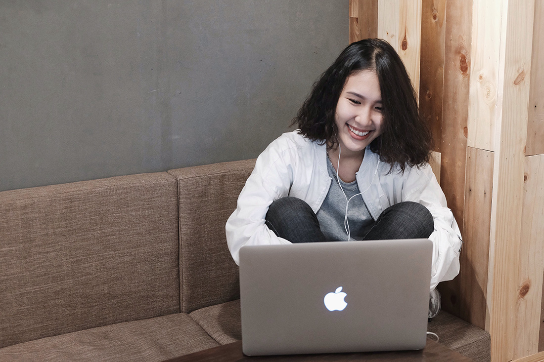 Student sitting on a couch and talking skying on the computer.