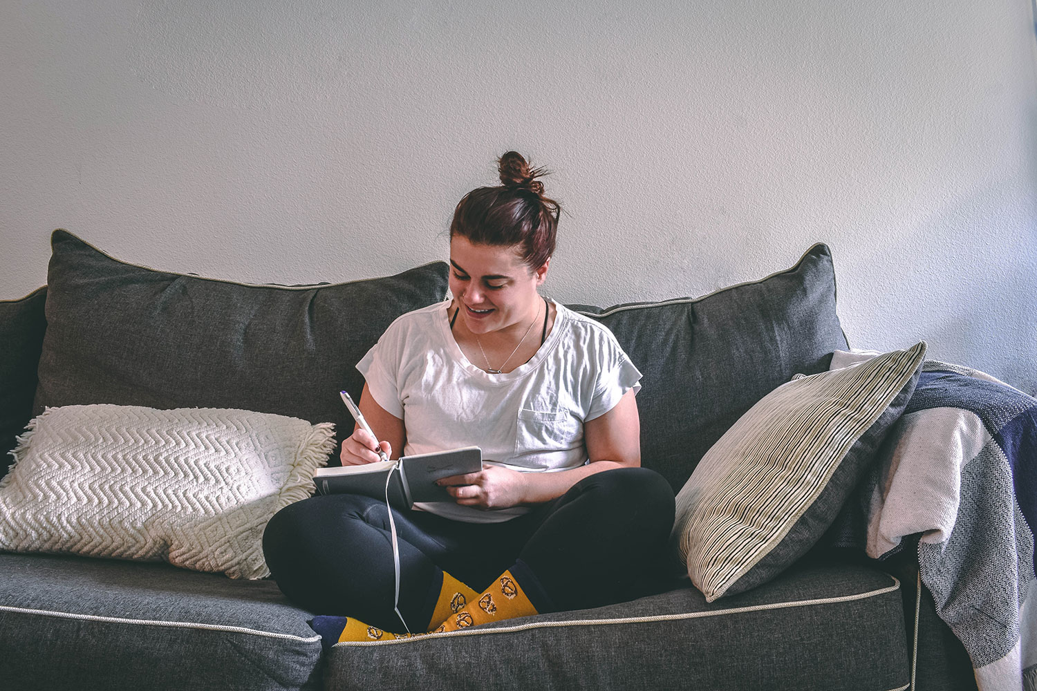 student sitting on a couch and writing in a notebook