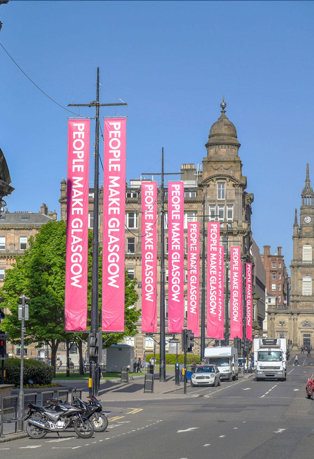 Street view of Glasgow's George Street looking towards George Square and St George's Tron Church (Nelson Mandela Place). with bright pink People Make Glasgow (the city's brand slogan) banners