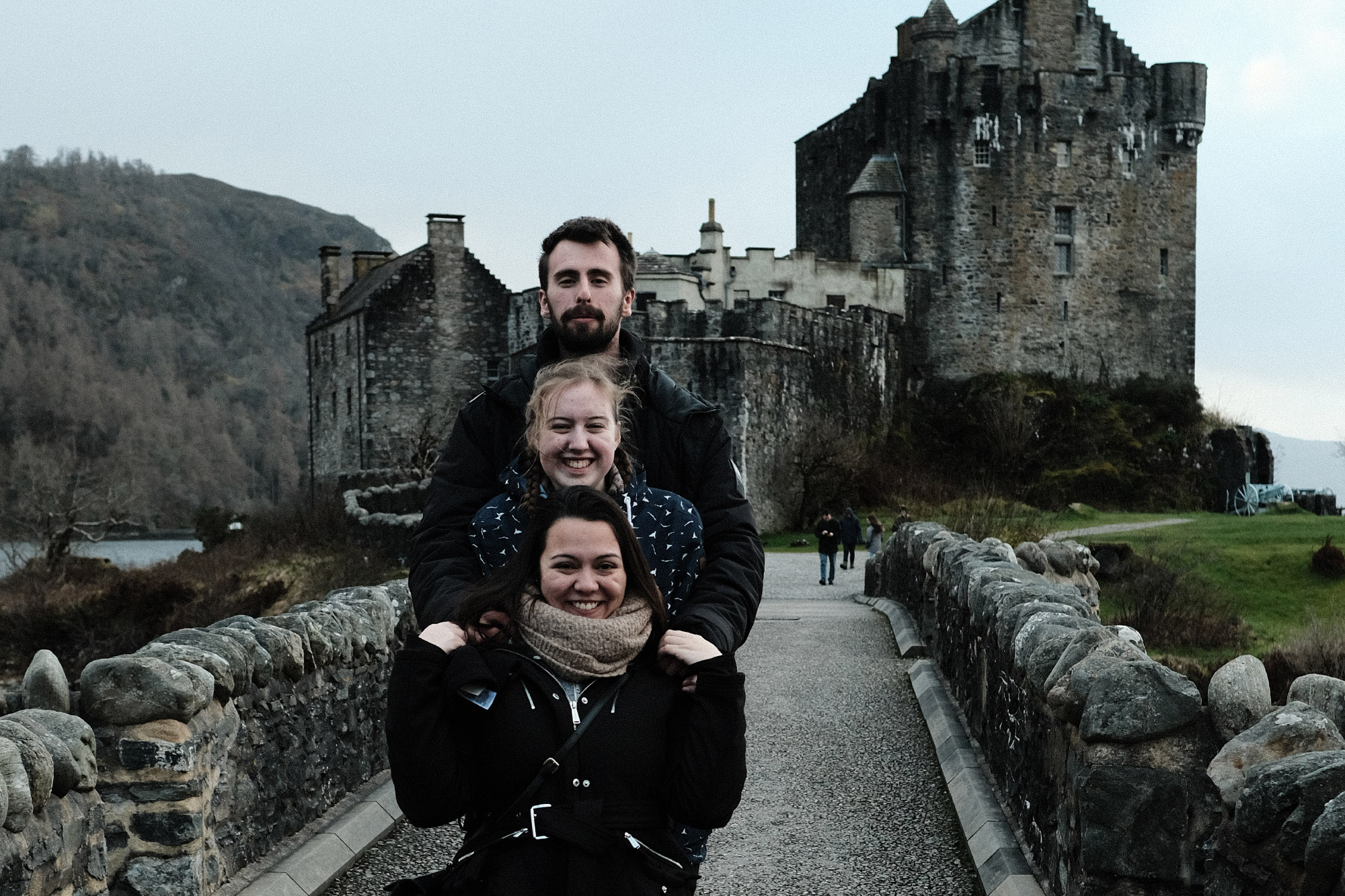 3 students pose at Eilean Donan Castle in Scotland.