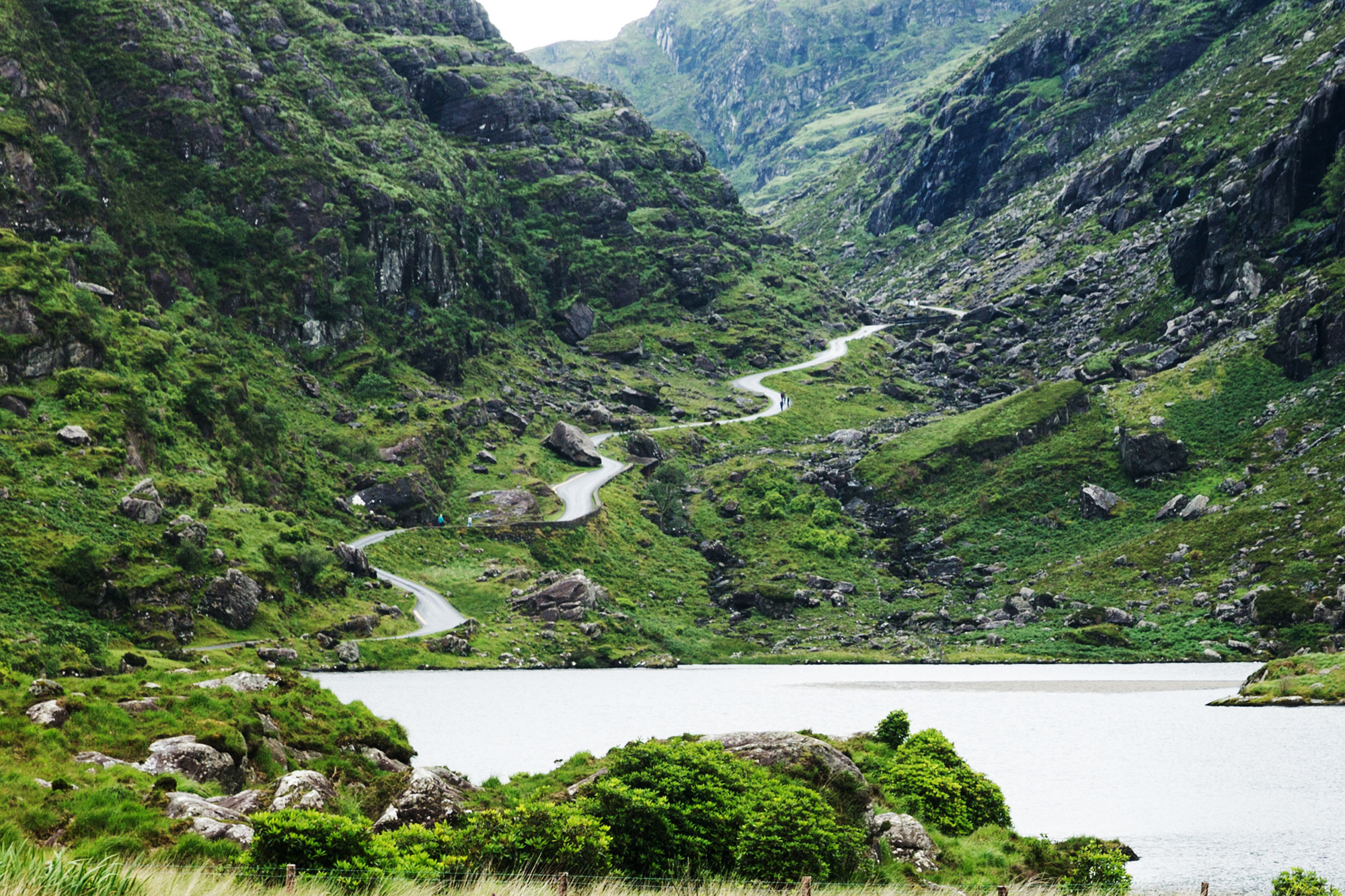 Green rugged mountain pass with windy road and lake at the Gap of Dunloe in County Kerry, Ireland.