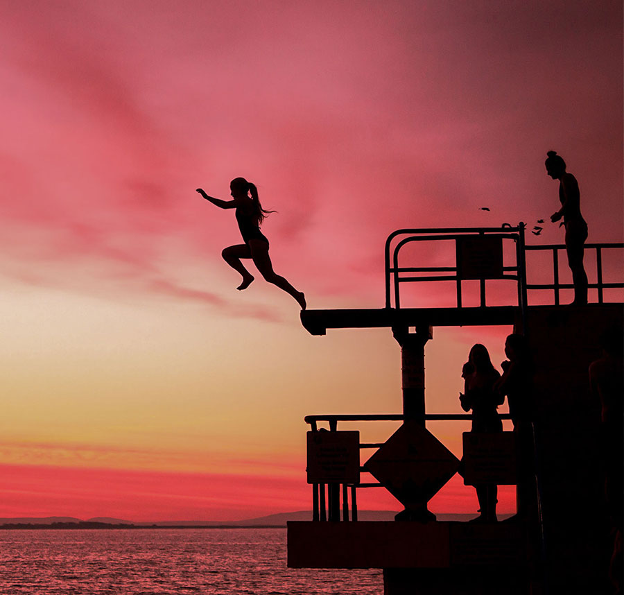 Person jumps off Blackrock Diving Tower at sunset, Galway, Ireland