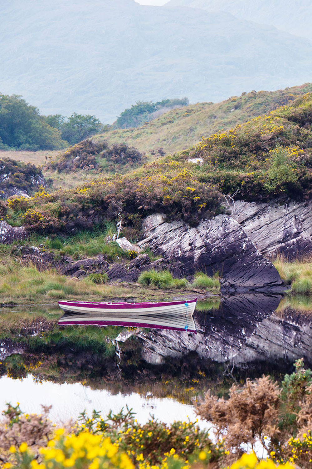 Rugged landscape with boats moored on a lake in Killarney National Park in the south west of Ireland.