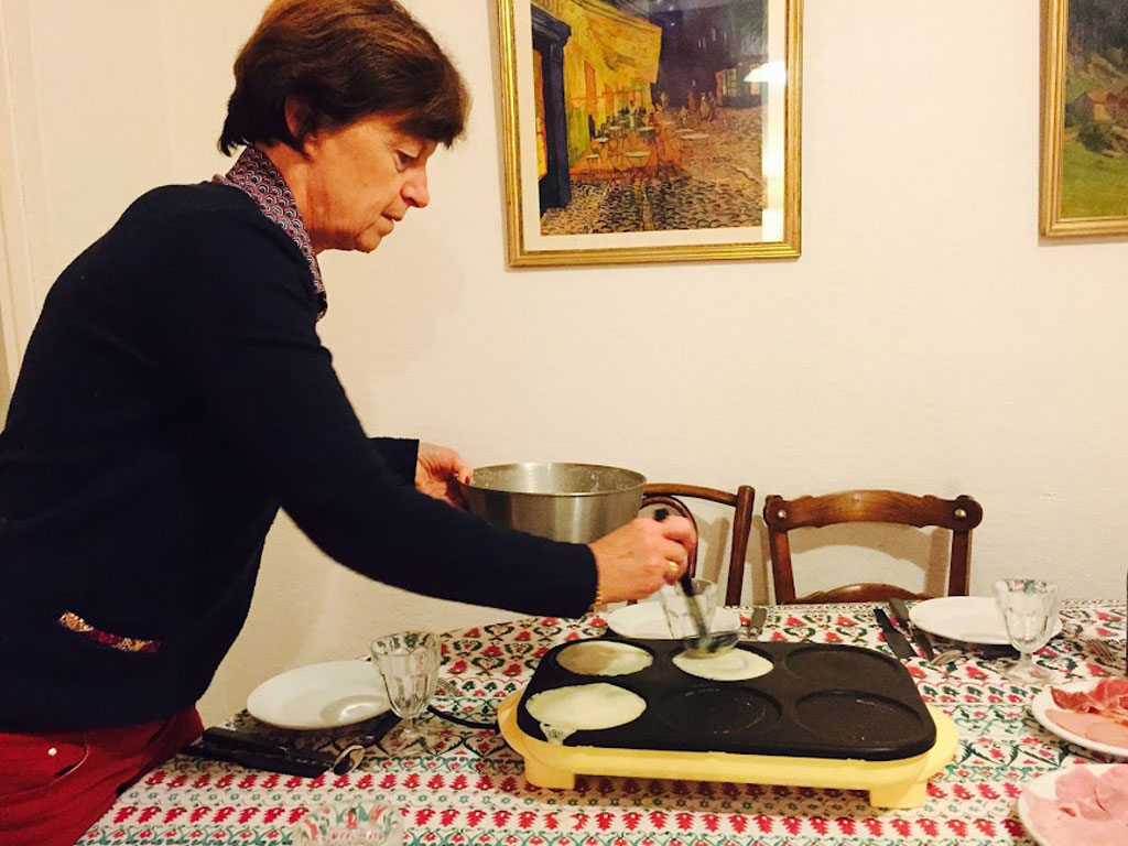 Sierra's host mom flipping crepes at the dining room table in Lyon, France.