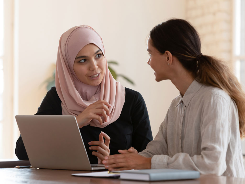 Two colleagues talking near a computer.