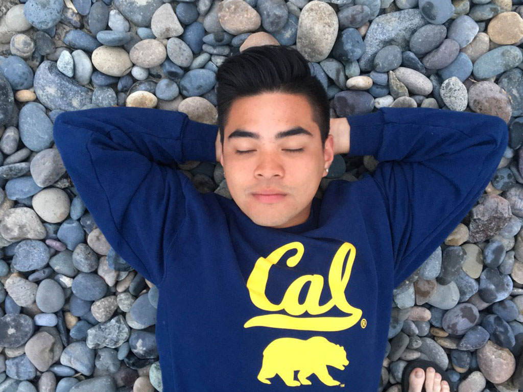 Ramil relaxing with his eyes closed on a bed of rocks