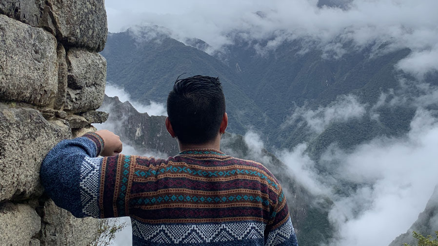 five-tips-to-incorporate-your-identity-into-the-study-abroad-experience-feature-image Ramil leaning against a stone wall looking out into nature.