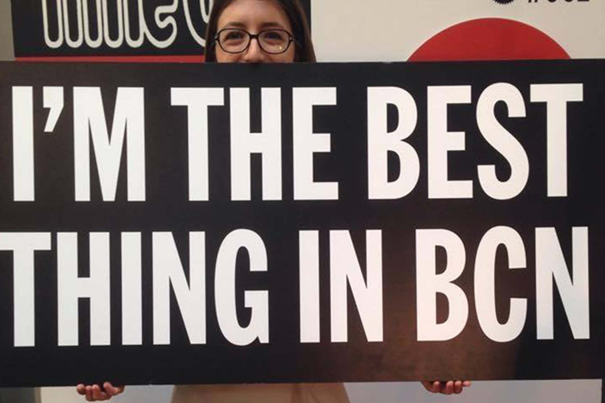 Claudia holds a sign that reads "I'm the best thing in BCN."
