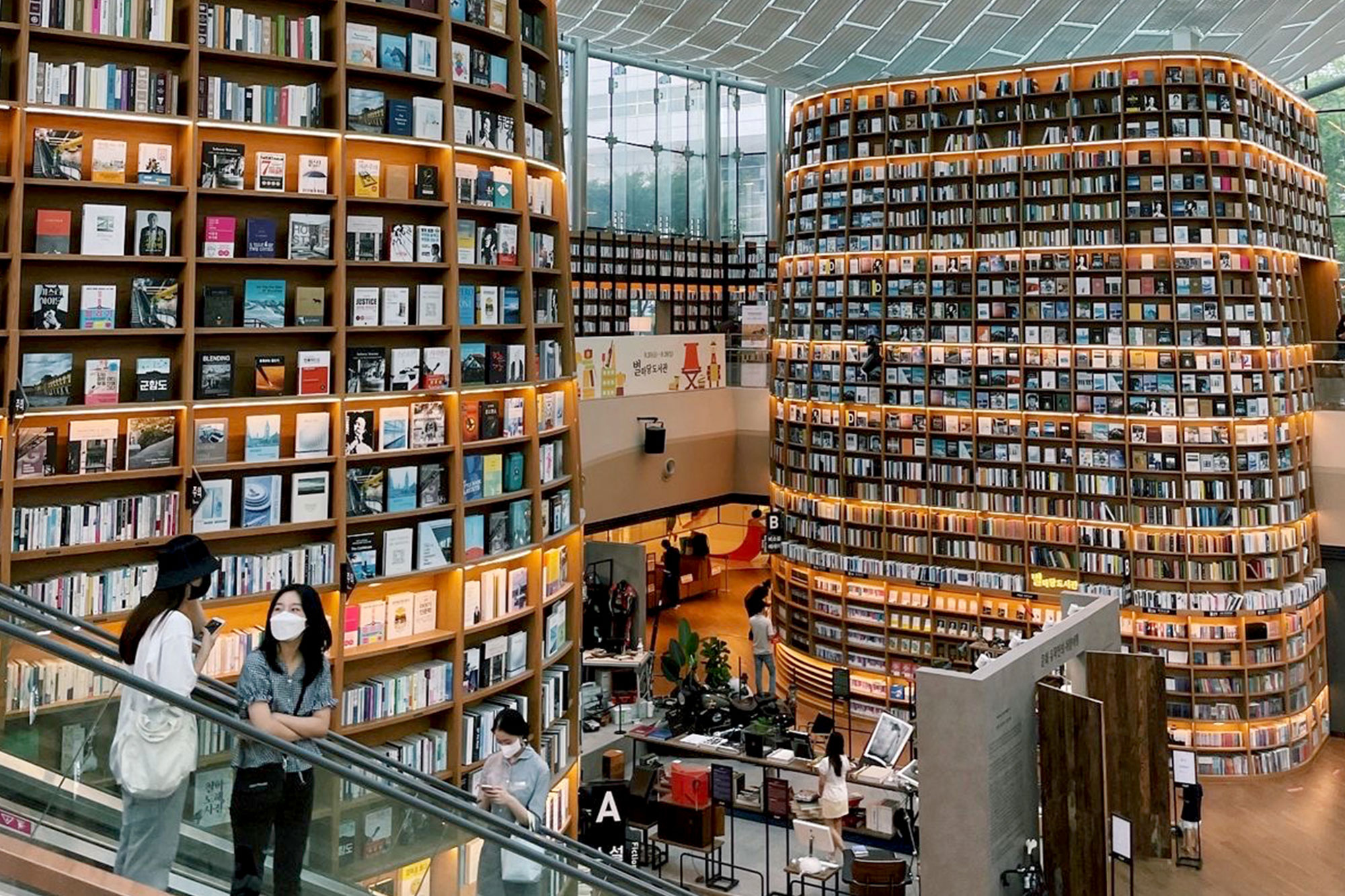 students on escalator in library with floor to ceiling bookshelves