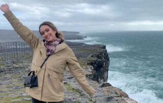 Student, arms raised, stand by the cliffs on the island of Inishmore, Ireland