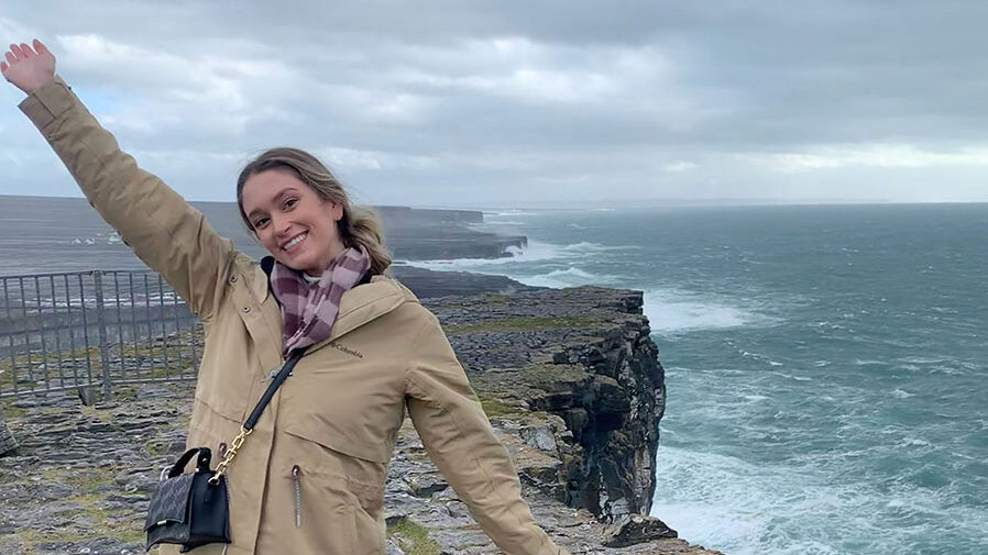 Student, arms raised, stand by the cliffs on the island of Inishmore, Ireland