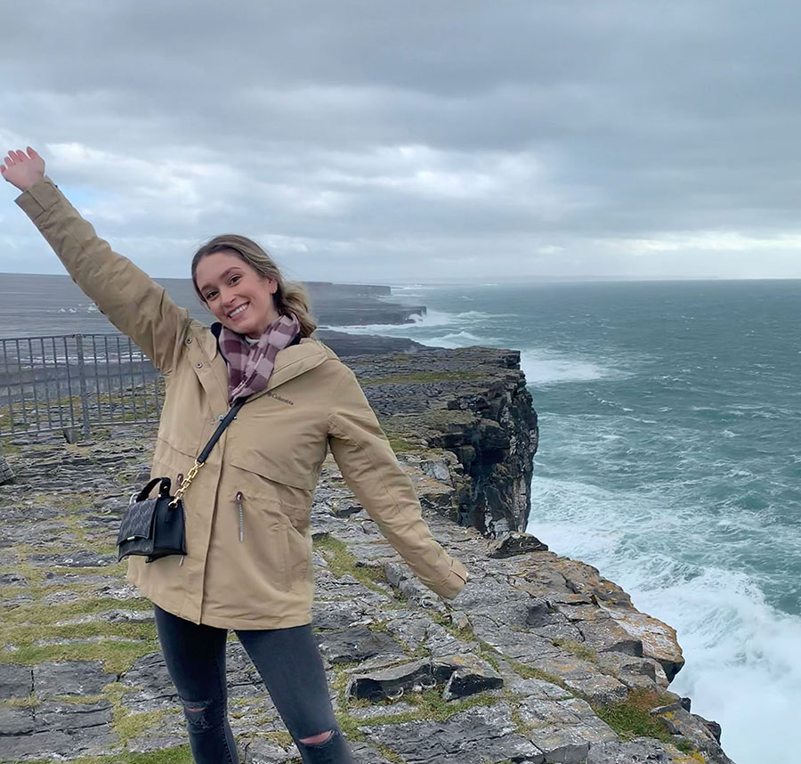 Student, arms raised, stand by the cliffs on the island of Inishmore, Ireland