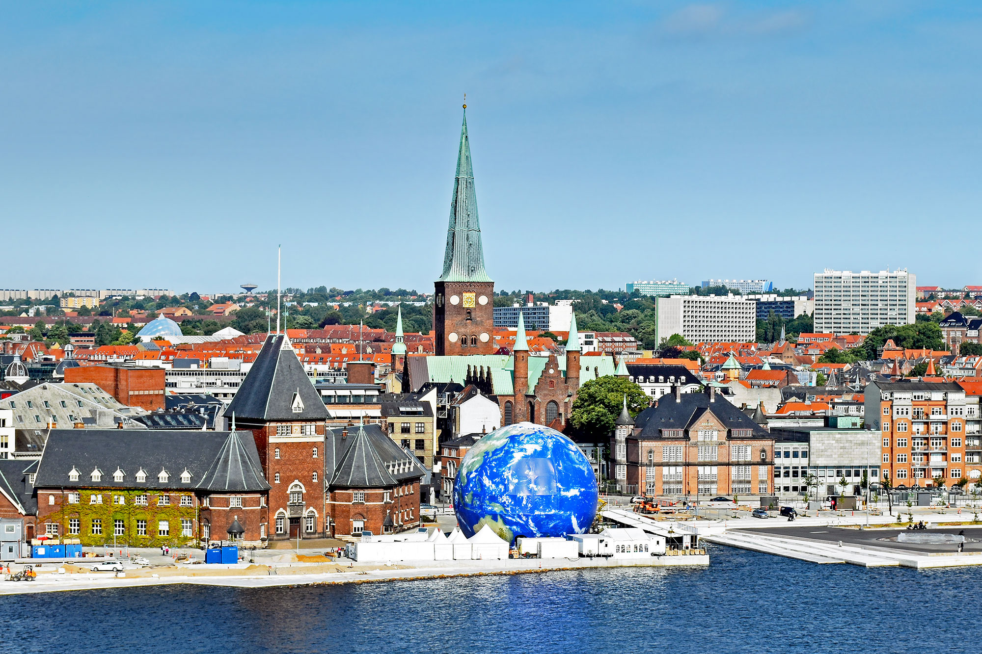 Cityscape of Arrhus, Denmark on a bright sunny day with harbor and blue and green earth globe sculpture