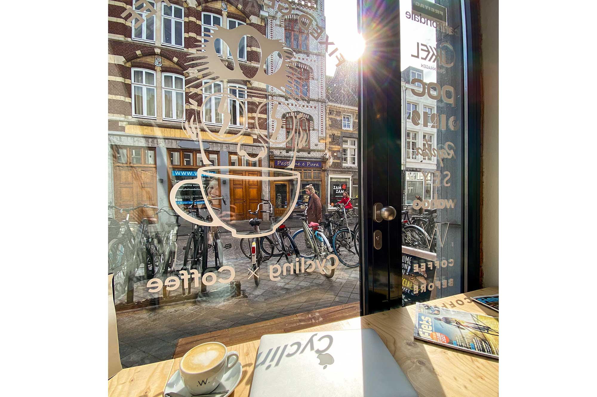 Coffee and laptop by a window with bikes outside at the Fixed Gear Cafe in Maastricht.