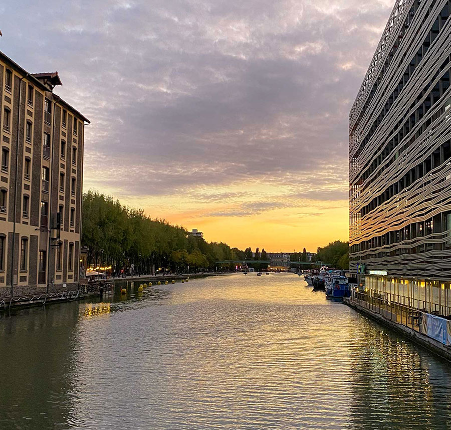 Hostel buildings along a river in Paris, France at sunset.