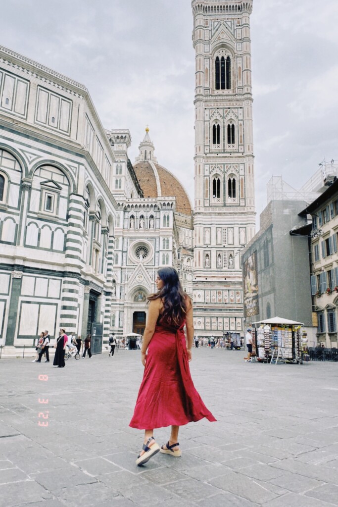 A young woman spins around in the stone streets in a red dress in Florence, Italy. 