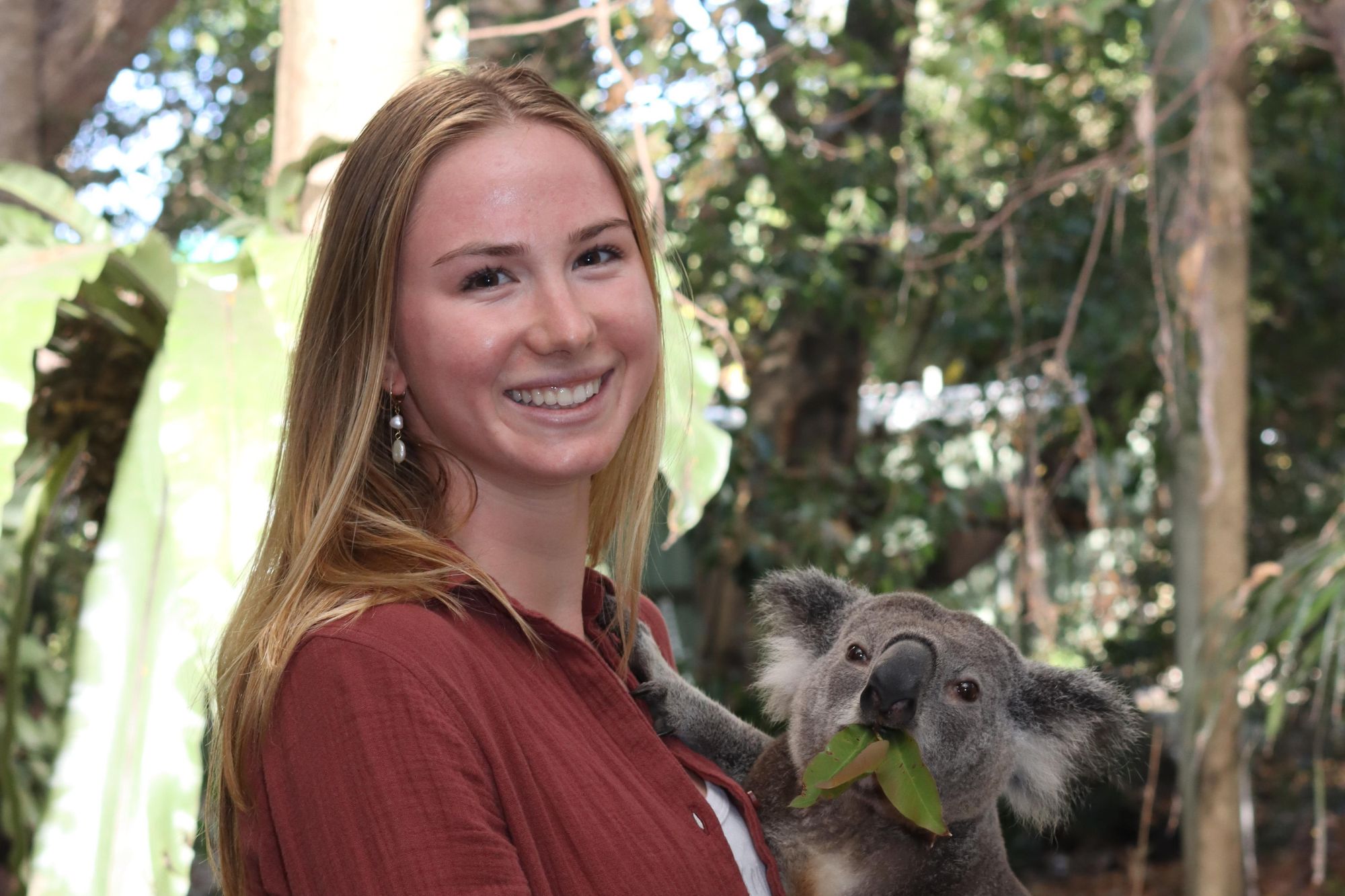 Dorienne holds a koala and smiles for a photo.