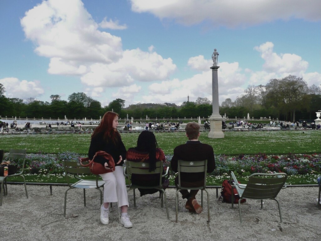 Three students facing a monument in a park.