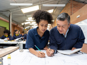 College students working together on a design project and drawing on a blueprint