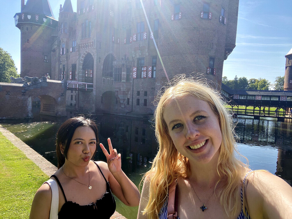 Two female students taking a self-taken photo with castle and rays of sunshine in the background