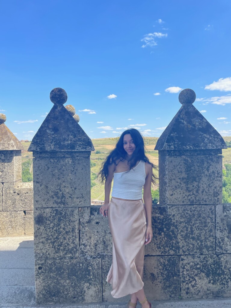 female student standing between two stone columns