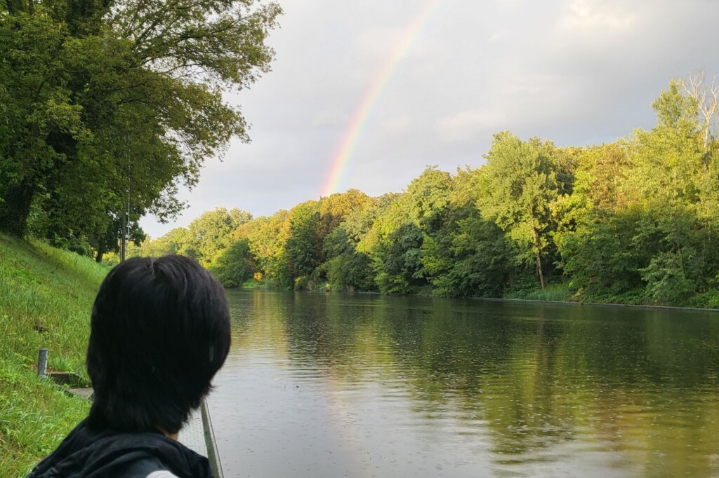 Rainbow over a river with student looking on