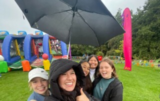 Valerie Cruz with friends under an umbrella in the rain of Ireland
