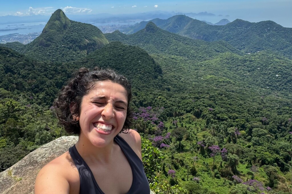 UCB student on a hike in Brazil smiling above green landscape