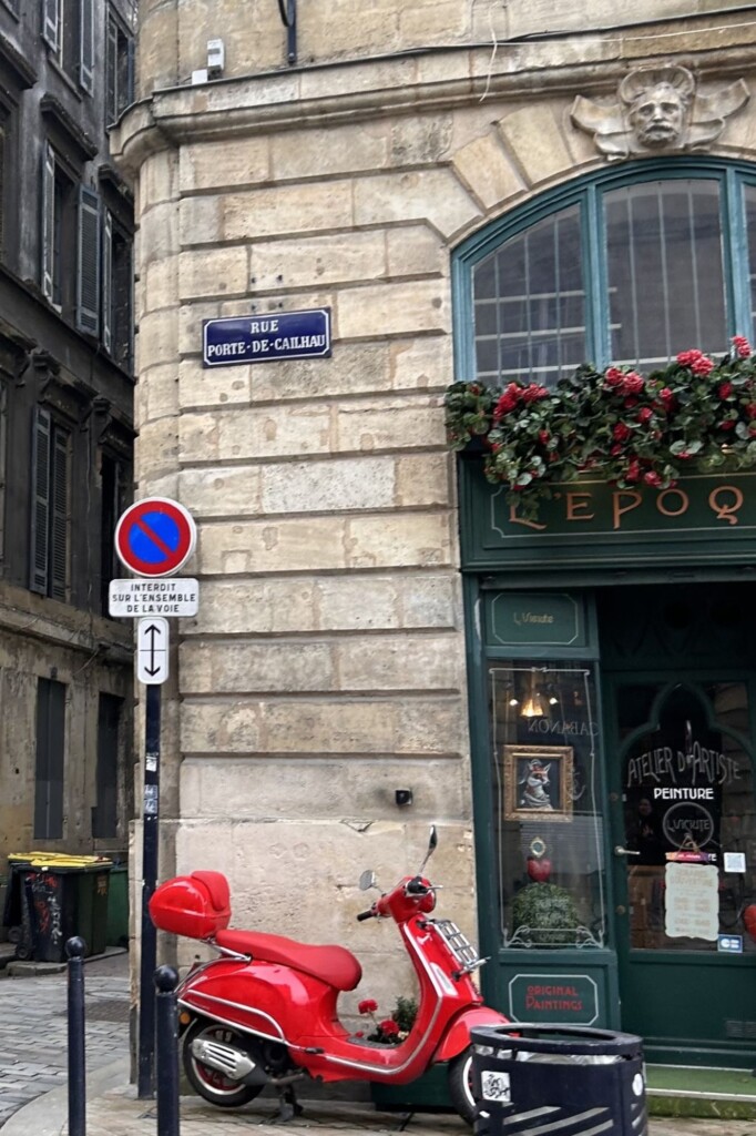 Street in Bordeaux with red Vespa in front of store